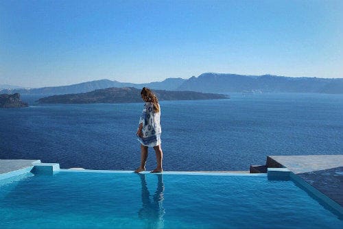 Everything about Eurail | Girl walking on the side of swimming pool iin santorini, Greece